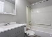 Thumbnail 14 of 16 - A white bathroom with a toilet, sink, and bathtub.