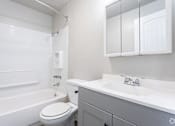 Thumbnail 16 of 16 - A white bathroom with a toilet, sink, and bathtub.
