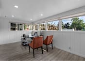 Thumbnail 5 of 18 - A room with a desk and chairs with a window in the background.