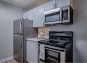 Thumbnail 11 of 18 - A kitchen with a stainless steel refrigerator, microwave, and oven.