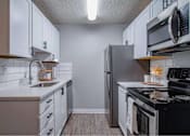 Thumbnail 8 of 18 - A kitchen with white cabinets and black appliances.