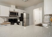 Thumbnail 6 of 13 - A kitchen with white cabinets and a granite countertop.
