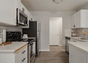 Thumbnail 10 of 13 - A kitchen with white cabinets and a black refrigerator.