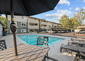 Thumbnail 11 of 18 - A pool surrounded by wooden deck chairs and umbrellas.