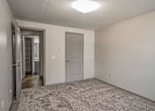 Thumbnail 5 of 18 - A room with a carpeted floor and a door on the right.