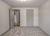 Thumbnail 8 of 18 - A room with a carpeted floor and two doors.