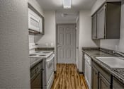 Thumbnail 10 of 18 - A kitchen with a white oven and microwave, a white door, and a white sink.