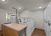 Thumbnail 12 of 15 - A laundry room with a counter and washers and dryers.