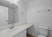 Thumbnail 14 of 15 - A white bathroom with a toilet, sink, and mirror.