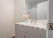 Thumbnail 8 of 15 - A white bathroom sink with a vase of flowers on top.