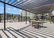 Thumbnail 20 of 25 - A patio with a table and chairs under a roof.