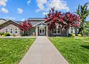 Thumbnail 6 of 25 - A building with a stone facade and a green lawn in front.