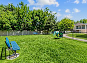Thumbnail 2 of 25 - A green lawn with a blue chair and a green bench.