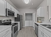 Thumbnail 21 of 25 - A modern kitchen with white cabinets and stainless steel appliances.