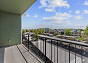 Thumbnail 15 of 25 - A balcony with a metal railing overlooks a street with cars and houses.