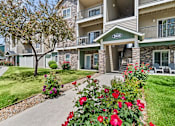 Thumbnail 1 of 25 - Apartment building with red flowers in front.