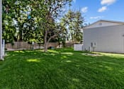 Thumbnail 32 of 34 - A backyard with a green lawn and a white fence.