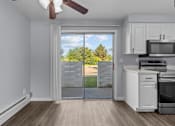 Thumbnail 5 of 34 - A kitchen with a white oven and microwave, a ceiling fan, and a sliding glass door leading to a backyard.