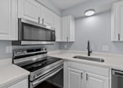 Thumbnail 4 of 34 - A modern kitchen with a black microwave above the stove.
