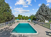 Thumbnail 25 of 34 - A large outdoor swimming pool surrounded by a fence and trees.