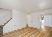 Thumbnail 7 of 34 - A room with wooden floors and white walls, a staircase, and a window with blinds.