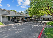 Thumbnail 33 of 34 - A sunny day at a residential complex with cars parked in the driveway.
