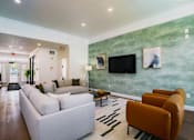 Thumbnail 1 of 61 - A living room with a white couch and a green wall.
