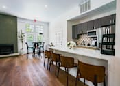 Thumbnail 4 of 61 - A kitchen with a white counter top and wooden chairs.