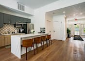 Thumbnail 5 of 61 - A kitchen with a white counter top and brown chairs.