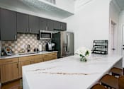 Thumbnail 6 of 61 - A kitchen with a white counter top and wooden cabinets.