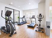 Thumbnail 10 of 61 - A room with a treadmill, elliptical trainer, and other exercise equipment.