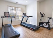 Thumbnail 11 of 61 - A room with a treadmill, a stationary bike, and a rowing machine.