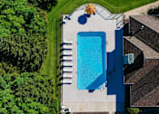 Thumbnail 23 of 61 - A swimming pool surrounded by a concrete deck and a house with a brown roof.