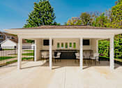 Thumbnail 25 of 61 - A white covered patio with a table and chairs.