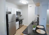 Thumbnail 27 of 61 - A kitchen with a black counter top and stainless steel appliances.