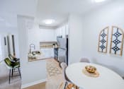 Thumbnail 32 of 61 - A kitchen with a table and chairs in the foreground and a refrigerator in the background.