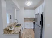 Thumbnail 33 of 61 - A kitchen with granite countertops and white cabinets.