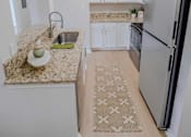 Thumbnail 34 of 61 - A kitchen with a granite countertop and a refrigerator.