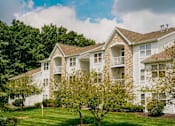 Thumbnail 44 of 61 - A white apartment building with a green lawn in front.