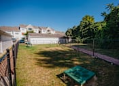 Thumbnail 46 of 61 - A backyard with a green trampoline and a fence.
