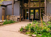 Thumbnail 51 of 61 - A building with a brown roof and glass windows is surrounded by greenery.