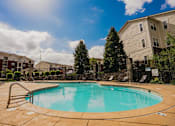 Thumbnail 1 of 36 - A swimming pool surrounded by a stone wall and trees.