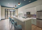 Thumbnail 7 of 36 - A kitchen with a white counter and blue chairs.