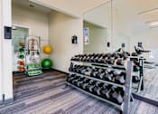 Thumbnail 11 of 36 - A gym room with a mirror, weights, and exercise equipment.