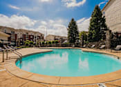 Thumbnail 16 of 36 - A swimming pool in a residential area with a clear blue sky.