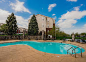 Thumbnail 17 of 36 - A swimming pool surrounded by a stone wall and trees.