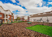 Thumbnail 19 of 36 - A playground with a green surface and a swing set.