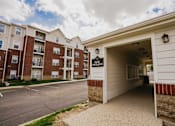 Thumbnail 21 of 36 - The entrance to a Pwylon apartment complex with a parking lot in front.