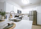 Thumbnail 23 of 36 - A kitchen with white cabinets and a stainless steel refrigerator.