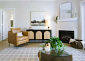 Thumbnail 28 of 36 - A living room with a fireplace and a painting on the wall.